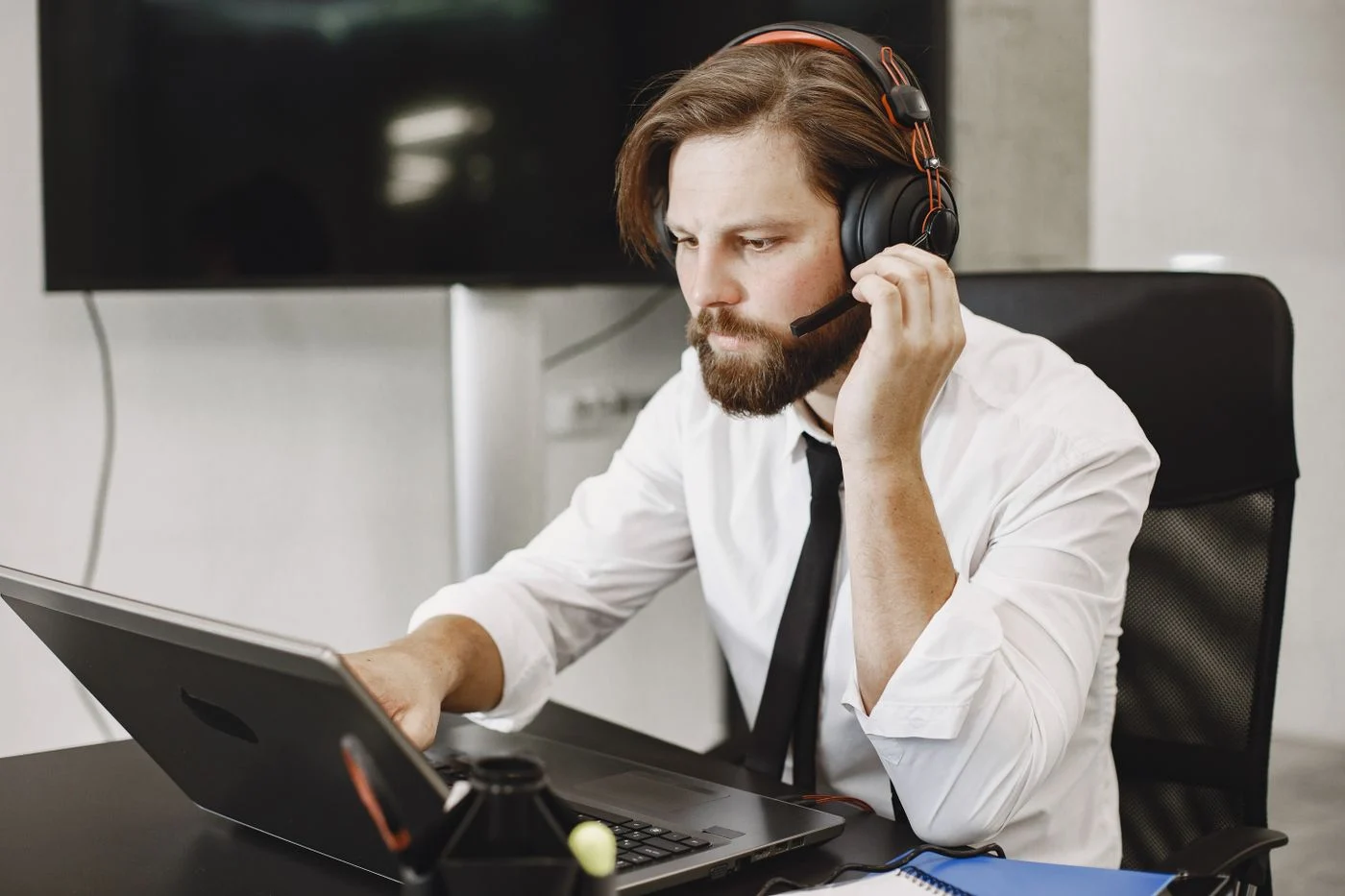 Un professionnel équipé d’un casque travaille sur un ordinateur portable dans un bureau